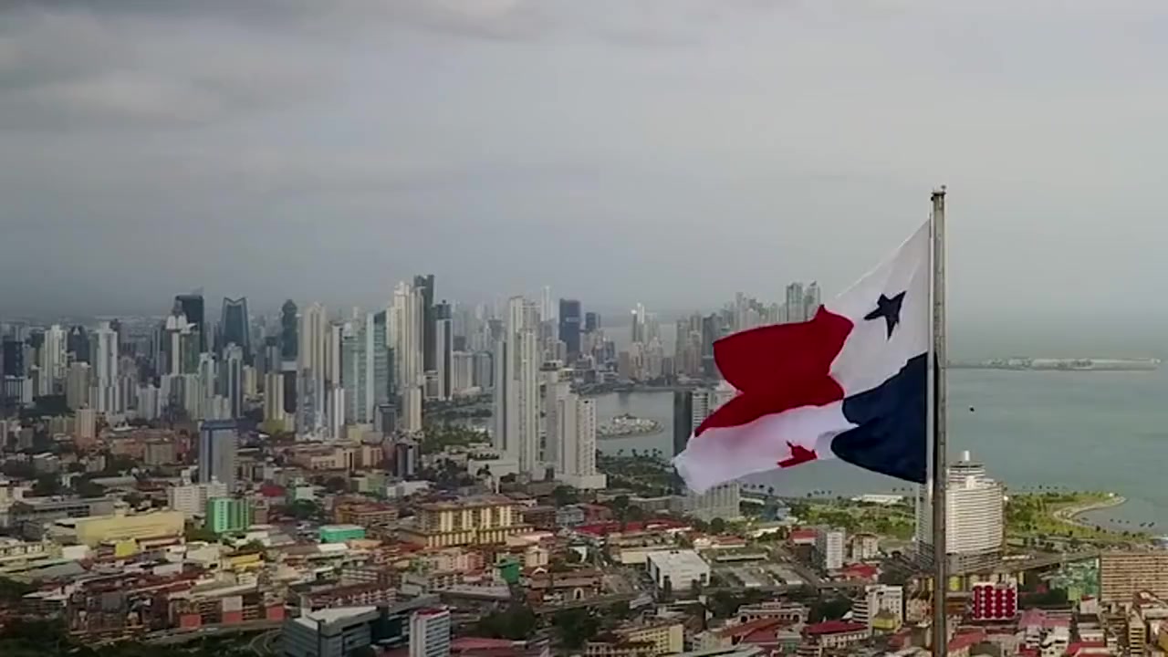 Panamanian flag above Panama City, opening an illustrative montage of regional markets, an airborne drone, military training, and firefighters responding to a building fire