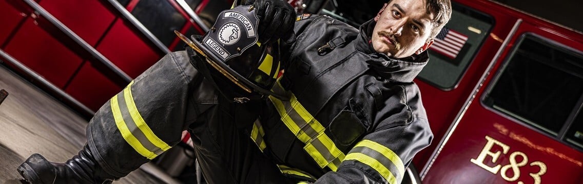 Firefighter wearing LION V-Force EVO turnout gear in a fire station truck bay